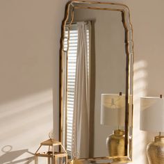 a large mirror sitting on top of a table next to a lamp and vases