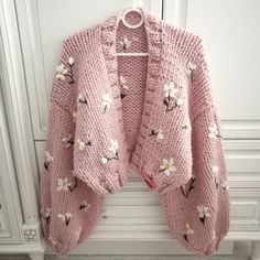 a pink cardigan sweater with flowers on it