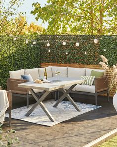 an outdoor patio with white furniture and string lights strung over the table, along with greenery