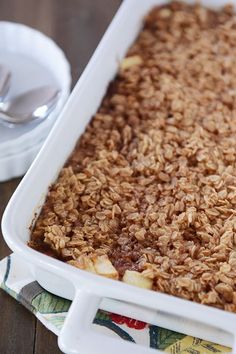 a white casserole dish filled with oatmeal sitting on top of a wooden table