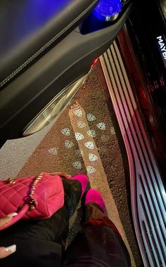 a person sitting on the floor in front of a car with their feet propped up