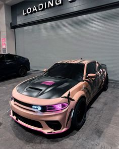 a pink and black car is parked in front of a loading area with two cars