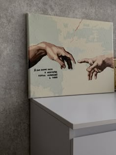 two hands reaching for each other on a white shelf next to a gray and grey wall