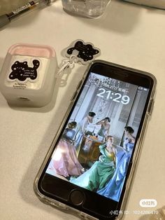 a cell phone sitting on top of a table next to a container with an earphone plug in it