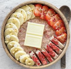 a bowl filled with oatmeal, bananas and strawberries next to a spoon