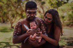 a man and woman holding a baby in their arms