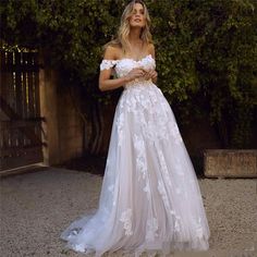 a woman in a white wedding dress standing outside