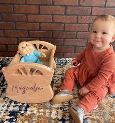 a baby sitting on the floor next to a wooden toy