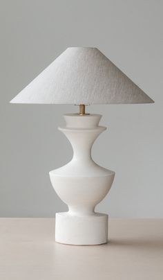 a white table lamp sitting on top of a wooden table