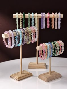 several bracelets are displayed on wooden stands with beads hanging from the top and below them