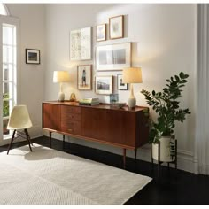 a living room scene with focus on the sideboard and chair, framed pictures above it