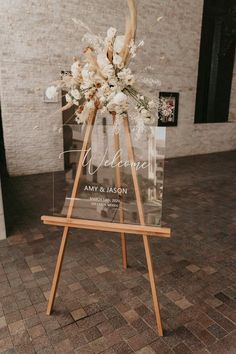 an easel with flowers on it is sitting in the middle of a brick floor