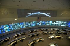 an office building with many desks and monitors on the wall, all in circular shape