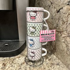 hello kitty coffee mugs are stacked on top of each other in front of a microwave