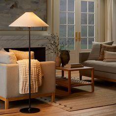 a living room filled with furniture and a lamp on top of a wooden coffee table