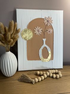 a white vase with flowers sitting on top of a wooden table next to some beads