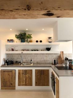 an open kitchen with wooden cabinets and white counter tops is pictured in this image, there are potted plants on the shelf above the sink