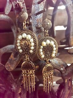 Exquisite one-of-a-kind drop earring. Done in antique gold finishing with beautiful carvings. The delicate pearls are beautiful, and pairs well with the show stopping metal fringe.

The Leah earring will pair amazing with any Dreamers & Lovers dress. It is the perfect earring option for the bohemian bride.

- Clip on style Elegant Antique Finish Earrings For Festive Occasions, Ornate Dangle Chandelier Earrings With Pearl Drop, Ornate Chandelier Earrings With Pearl Drop, Elegant Brass Earrings With Dangling Beads, Bohemian Pearl Earrings With Dangling Beads, Elegant Antique Gold Brass Chandelier Earrings, Vintage Gold Chandelier Earrings With Dangling Beads, Bohemian Pearl Earrings With Dangling Beads For Weddings, Elegant Bronze Earrings With Dangling Beads