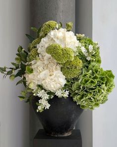 a black vase filled with white and green flowers