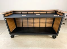 a black and wood cabinet with wheels on it