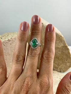 a woman's hand with a green ring on it