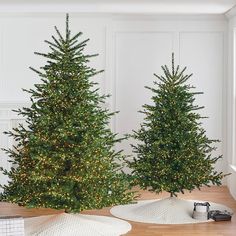 two artificial christmas trees are sitting on the floor