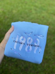 a person holding up a blue t - shirt with the year 1989 printed on it