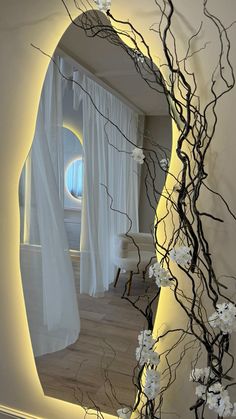 a room with white curtains and flowers on the wall, as seen through a mirror