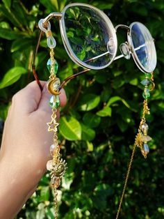 Elevate your eyewear game with our Green and gold glasses chain featuring a stunning combination of green prehnite and yellow citrine crystals. This unique glasses chain is perfect for those who love celestial themes, as it features moon, star, and sun charms that will make you feel out of this world! The chain comes in both gold and silver colors, making it a versatile accessory for any outfit. Plus, the prehinte and citrine crystals are believed to bring positive energy and abundance to your life, making this glasses chain not just a stylish accessory, but also a meaningful one. This eyeglass chain might be slightly heavier than regular chains because of some stone beads and crystals. Actual colors of any item or chains may slightly differ from screen to screen due to the screen resoluti Handmade Gold Glass Glasses Chains, Handmade Glass Glasses Chains In Gold, Gold Glass Glasses Chains For Festivals, Fantasy Glasses, Chains Aesthetic, Witchy Gifts, Unique Glasses, Glasses Chains, Gold Glasses