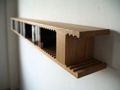 a wooden shelf with several books on it against a white wall in an empty room