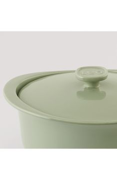 a large green pot with a lid on it's side and a white background