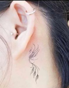 a woman's ear with a small bird tattoo on it