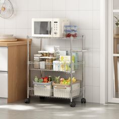 a microwave sitting on top of a metal shelf filled with fruit and veggies