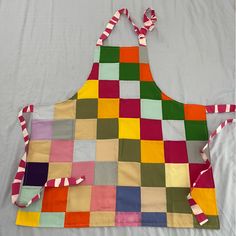 an apron made out of patchwork material on a white sheet with red, green, yellow and blue strips