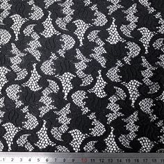 a black and white lace fabric with small flowers on the side, as well as a ruler