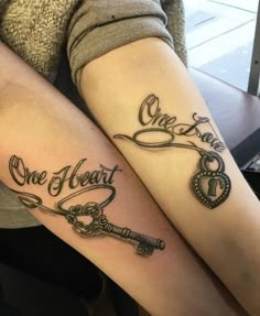 two people sitting next to each other with tattoos on their legs that say one heart