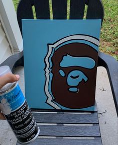 a hand holding a spray paint can next to a painting of a gorilla on a blue background