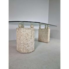 two vases sitting on top of each other in front of a glass table topped with rocks