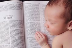 a baby laying on top of an open book with its head resting on it's hand