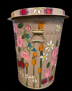 a flower pot with flowers painted on the front and sides, sitting against a black background