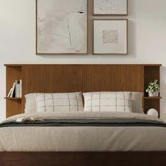 a bed with wooden headboard and two pictures above it