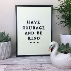 a white swan sitting in front of a black and white framed poster with words on it