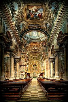 the inside of an old church with pews and paintings on the walls above it