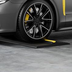 a grey car with yellow trim parked in a parking lot next to a black pole