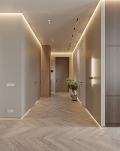 an empty hallway with wooden floors and white walls is lit by recessed lighting on either side