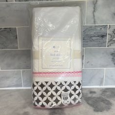 a white bed sheet sitting on top of a counter next to a blue tiled wall