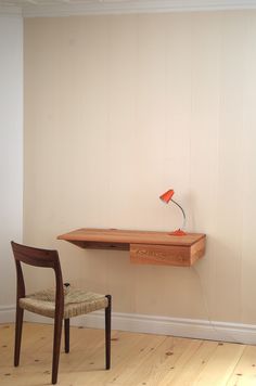 a wooden desk with a chair next to it and a lamp on the top shelf