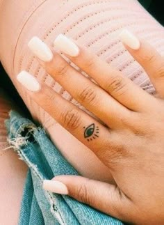 two hands holding each other with small tattoos on their fingers and the bottom half of them