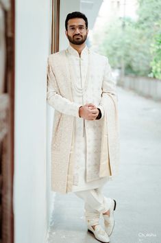 a man standing in front of a doorway wearing a white outfit