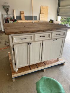 an unfinished kitchen island being built in a garage with wood flooring and cabinets on the side